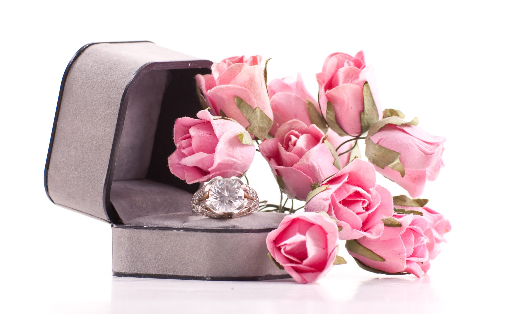 A diamond ring in a box with pink roses, to represent Custom Engagement Ring Design St. John.