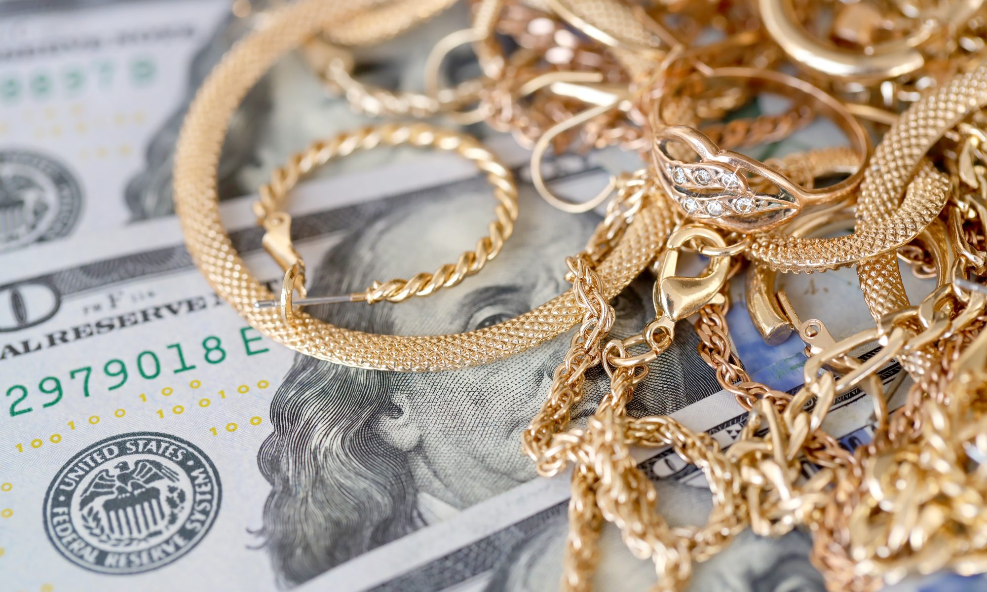 Gold jewelry on money bills to represent selling gold with gold buyer near Lowell.